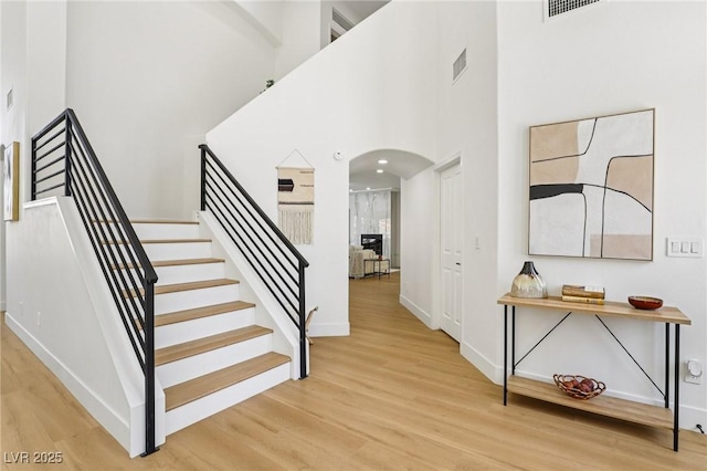 2469 Sun Reef Rd, Las Vegas, NV 89128 - staircase featuring arched walkways, wood finished floors, and a high ceiling