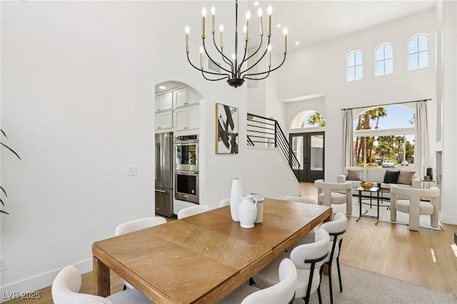 2469 Sun Reef Rd, Las Vegas, NV 89128 - dining space with arched walkways, stairway, a high ceiling, a chandelier, and light wood-type flooring