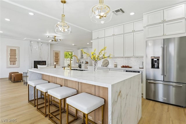 2469 Sun Reef Rd, Las Vegas, NV 89128 - kitchen with high end fridge, a chandelier, light wood-type flooring, recessed lighting, and light stone countertops