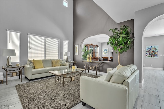 4435 Peaceful Harbor St, Las Vegas, NV 89129 - living room featuring arched walkways, plenty of natural light, a high ceiling, and light wood-style flooring