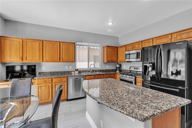 4435 Peaceful Harbor St, Las Vegas, NV 89129 - kitchen featuring appliances with stainless steel finishes, stone counters, a center island, brown cabinetry, and recessed lighting
