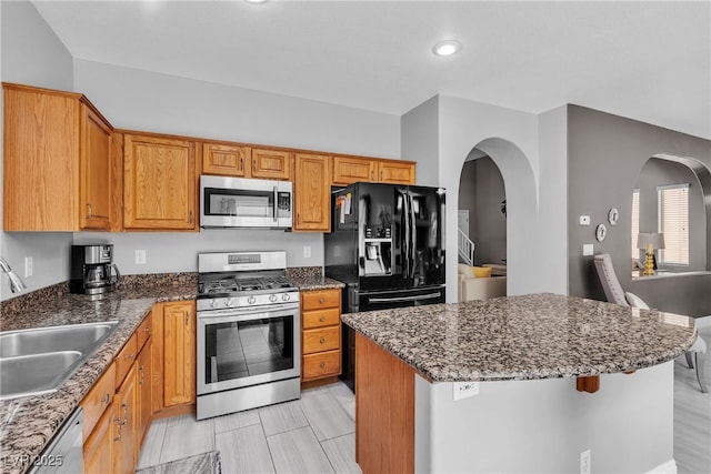 4435 Peaceful Harbor St, Las Vegas, NV 89129 - kitchen featuring stainless steel appliances, arched walkways, dark stone counters, a center island, and recessed lighting