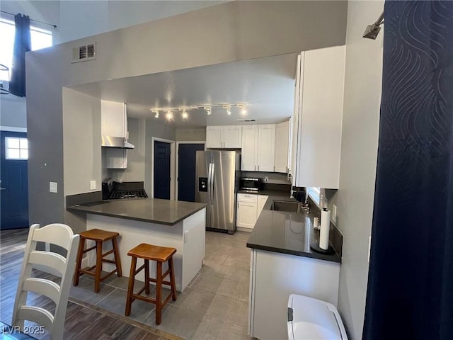 3736 Steinbeck Dr, Las Vegas, NV 89115 - kitchen with appliances with stainless steel finishes, dark countertops, a peninsula, under cabinet range hood, and plenty of natural light
