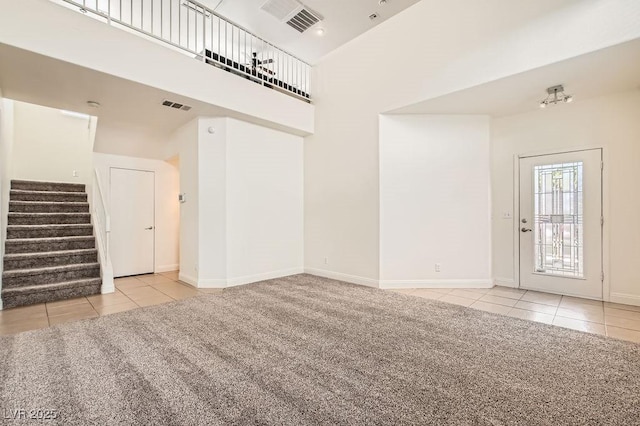 10413 Rising Harbor Ave, Las Vegas, NV 89129 - unfurnished living room featuring tile patterned floors, stairs, carpet flooring, and a towering ceiling