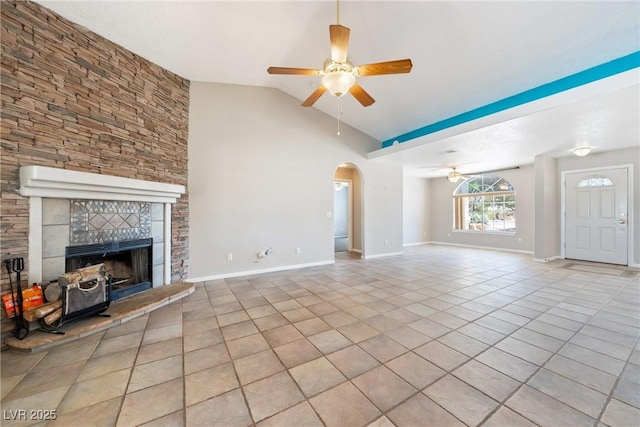 2950 Winchester Ave, Pahrump, NV 89048 - unfurnished living room featuring a ceiling fan, light tile patterned floors, a tile fireplace, lofted ceiling, and arched walkways