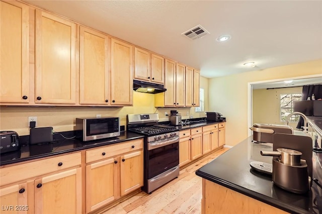 3168 Via Festiva, Henderson, NV 89044 - kitchen featuring stainless steel appliances, light brown cabinets, range hood, dark countertops, and light wood-type flooring
