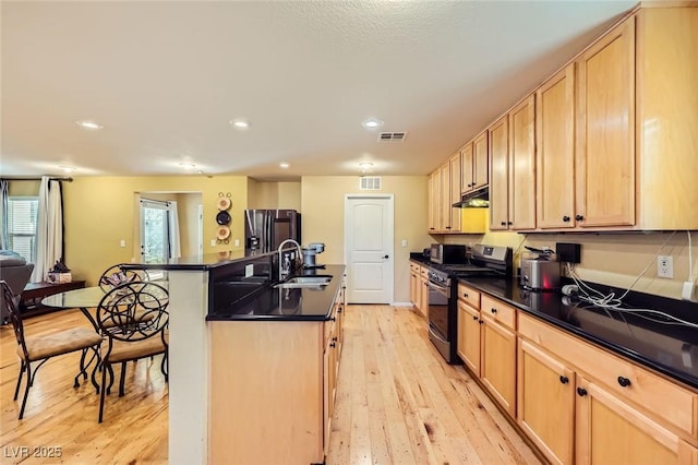 3168 Via Festiva, Henderson, NV 89044 - kitchen with stainless steel range with gas stovetop, refrigerator with ice dispenser, dark countertops, light wood-style floors, and recessed lighting