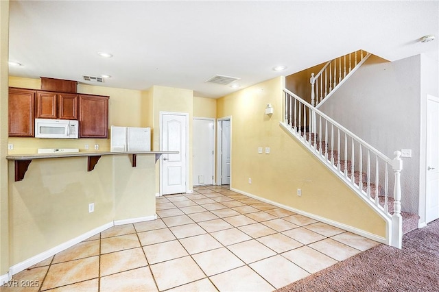 3905 Sweet Pine St Unit 102, Las Vegas, NV 89108 - kitchen with white appliances, a kitchen bar, light tile patterned flooring, recessed lighting, and a peninsula