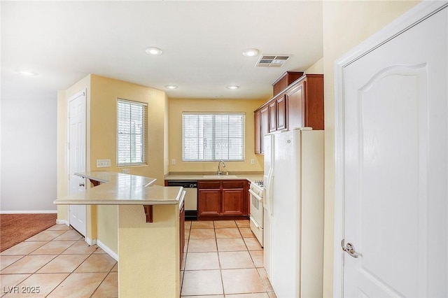 3905 Sweet Pine St Unit 102, Las Vegas, NV 89108 - kitchen with white appliances, a kitchen breakfast bar, light countertops, light tile patterned floors, and a peninsula