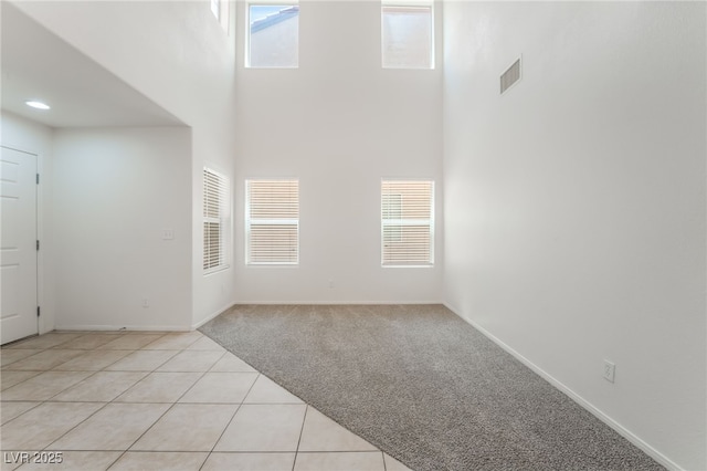 7553 Virginia Dale St, Las Vegas, NV 89131 - unfurnished room with a towering ceiling, plenty of natural light, light tile patterned floors, and light colored carpet