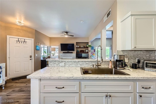 251 S Green Valley Pkwy Unit 3222, Henderson, NV 89012 - kitchen with ceiling fan, a peninsula, tasteful backsplash, dark wood-style floors, and white cabinetry