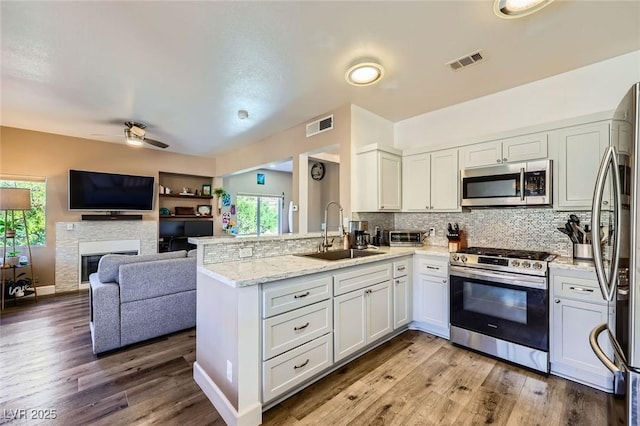 251 S Green Valley Pkwy Unit 3222, Henderson, NV 89012 - kitchen with stainless steel appliances, a peninsula, decorative backsplash, light stone counters, and wood finished floors
