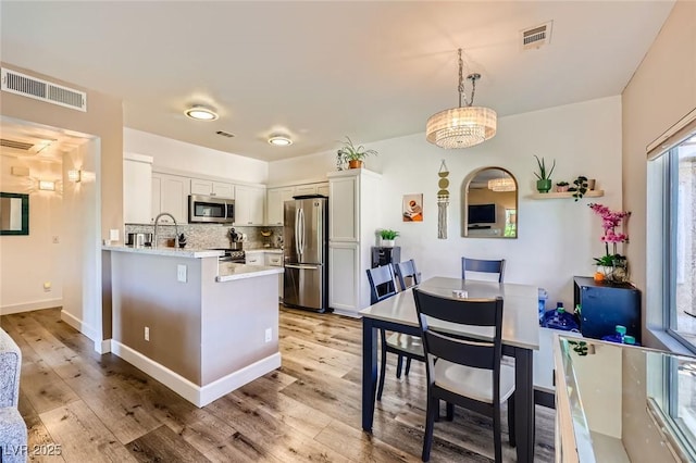 251 S Green Valley Pkwy Unit 3222, Henderson, NV 89012 - kitchen with appliances with stainless steel finishes, light countertops, light wood-style flooring, tasteful backsplash, and a peninsula