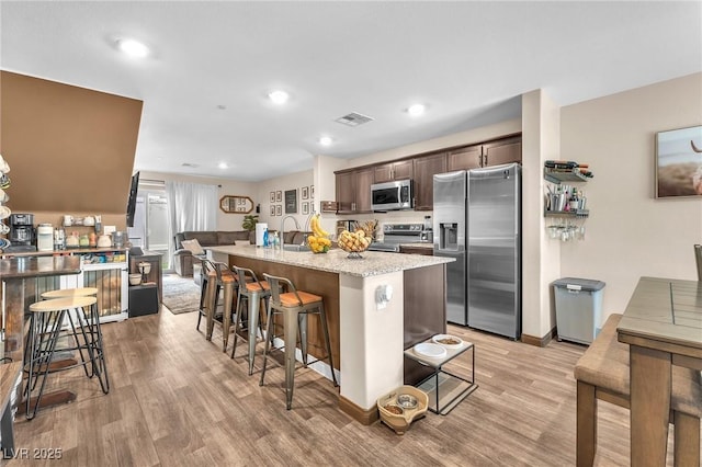 12280 Golden Wreath Rd Unit 3, Las Vegas, NV 89183 - kitchen featuring stainless steel appliances, a breakfast bar area, dark brown cabinets, light wood-type flooring, and recessed lighting