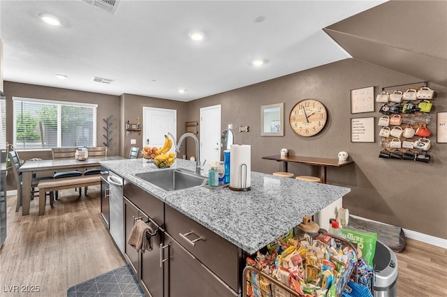 12280 Golden Wreath Rd Unit 3, Las Vegas, NV 89183 - kitchen featuring wood finished floors, recessed lighting, stainless steel dishwasher, an island with sink, and light stone countertops