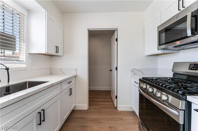 1648 J St, Las Vegas, NV 89106 - kitchen featuring appliances with stainless steel finishes, light wood-style flooring, and white cabinets
