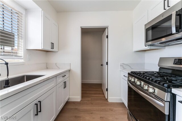 1648 J St, Las Vegas, NV 89106 - kitchen featuring appliances with stainless steel finishes, light wood-style floors, and white cabinetry