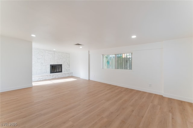 3320 Osage Ave, Las Vegas, NV 89101 - unfurnished living room with light wood-type flooring, a stone fireplace, and recessed lighting