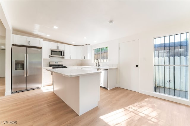 3320 Osage Ave, Las Vegas, NV 89101 - kitchen with stainless steel appliances, light wood-style flooring, a center island, white cabinets, and light countertops