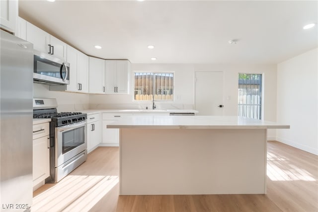 3320 Osage Ave, Las Vegas, NV 89101 - kitchen featuring stainless steel appliances, a center island, light wood finished floors, light countertops, and white cabinets
