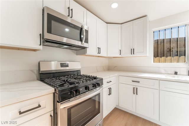 3320 Osage Ave, Las Vegas, NV 89101 - kitchen featuring stainless steel appliances, white cabinets, light stone counters, light wood-style floors, and recessed lighting