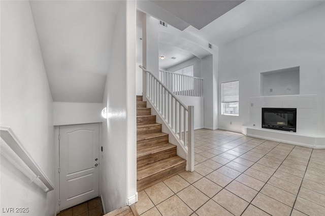 2766 Red Vista Ct, Henderson, NV 89074 - stairway featuring tile patterned floors, a towering ceiling, and a tiled fireplace