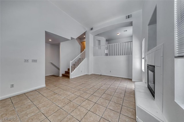 2766 Red Vista Ct, Henderson, NV 89074 - unfurnished living room featuring light tile patterned flooring, stairway, a glass covered fireplace, recessed lighting, and a towering ceiling