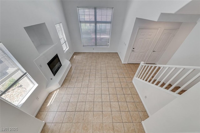 2766 Red Vista Ct, Henderson, NV 89074 - foyer entrance with light tile patterned flooring, a glass covered fireplace, a towering ceiling, and stairway