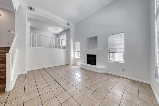 2766 Red Vista Ct, Henderson, NV 89074 - unfurnished living room featuring a towering ceiling, light tile patterned floors, and a fireplace with raised hearth