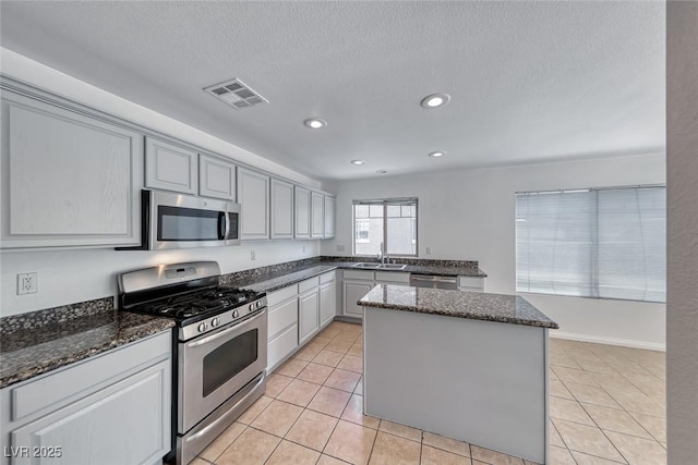 2766 Red Vista Ct, Henderson, NV 89074 - kitchen featuring appliances with stainless steel finishes, a center island, dark stone countertops, light tile patterned floors, and recessed lighting