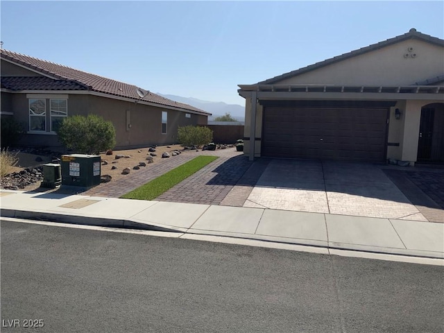 5363 S Juneau St, Pahrump, NV 89061 - view of front facade with decorative driveway, a tiled roof, an attached garage, and stucco siding