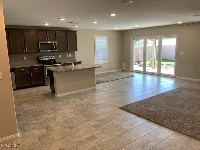 5363 S Juneau St, Pahrump, NV 89061 - kitchen featuring appliances with stainless steel finishes, open floor plan, dark brown cabinetry, stone countertops, and backsplash