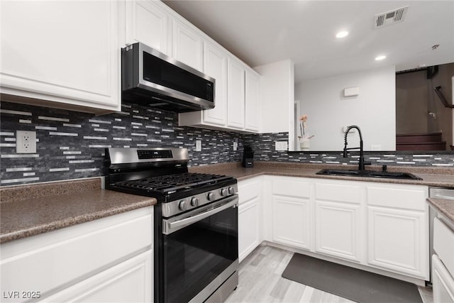 5620 Siena Rose St, North Las Vegas, NV 89031 - kitchen featuring appliances with stainless steel finishes, white cabinetry, tasteful backsplash, light wood-style floors, and recessed lighting