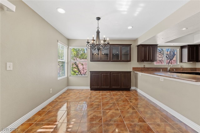 9409 Kayla Ct, Las Vegas, NV 89134 - kitchen with a chandelier, dark brown cabinetry, recessed lighting, tile patterned floors, and glass insert cabinets