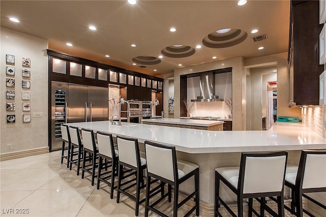 15 Golden Sunray Ln, Las Vegas, NV 89135 - kitchen with wall chimney range hood, light countertops, a kitchen breakfast bar, a large island, and recessed lighting