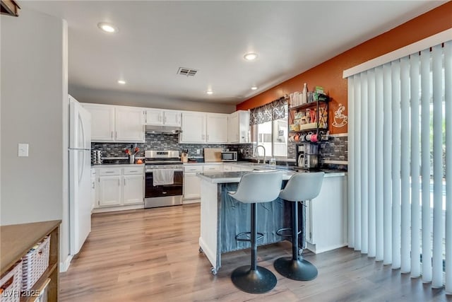 1048 Menands Ave, Las Vegas, NV 89123 - kitchen with appliances with stainless steel finishes, under cabinet range hood, a peninsula, decorative backsplash, and white cabinetry