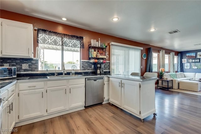 1048 Menands Ave, Las Vegas, NV 89123 - kitchen with stainless steel appliances, a peninsula, white cabinetry, light wood-style flooring, and backsplash