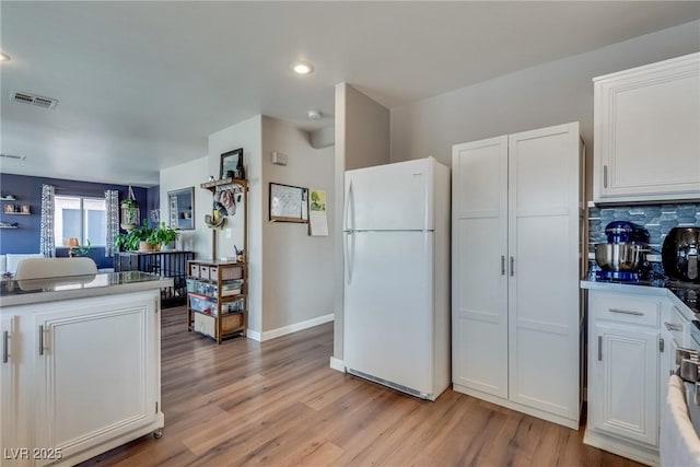 1048 Menands Ave, Las Vegas, NV 89123 - kitchen featuring freestanding refrigerator, white cabinets, light wood-type flooring, decorative backsplash, and recessed lighting