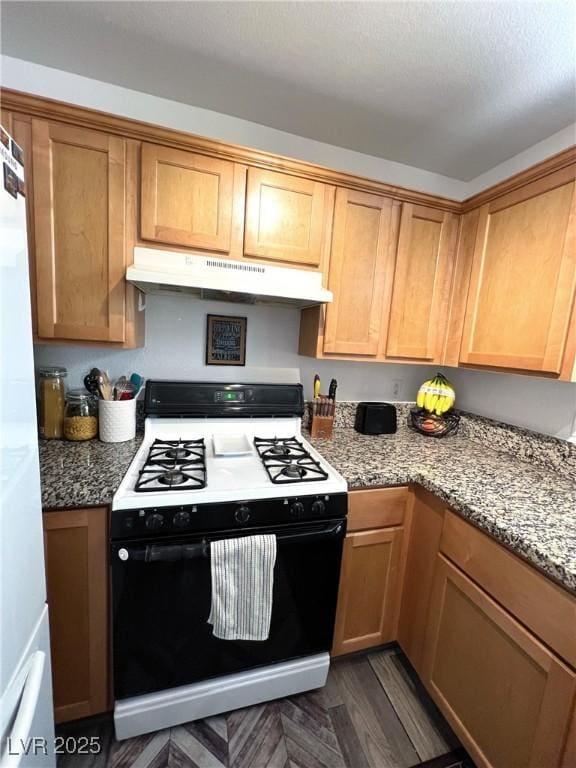 39 Belle La Blanc Ave, Las Vegas, NV 89123 - kitchen featuring black gas range, under cabinet range hood, freestanding refrigerator, light stone counters, and dark wood-style flooring