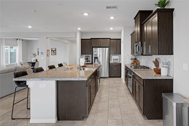 5234 Savannah Rose St, Las Vegas, NV 89149 - kitchen with stainless steel appliances, a breakfast bar area, dark brown cabinets, tasteful backsplash, and open floor plan