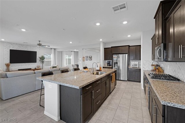 5234 Savannah Rose St, Las Vegas, NV 89149 - kitchen with appliances with stainless steel finishes, a breakfast bar area, a ceiling fan, an island with sink, and tasteful backsplash
