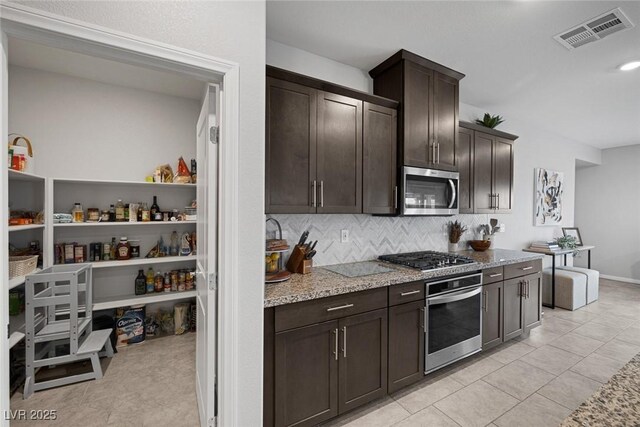 5234 Savannah Rose St, Las Vegas, NV 89149 - kitchen with appliances with stainless steel finishes, dark brown cabinets, backsplash, light stone counters, and light tile patterned floors