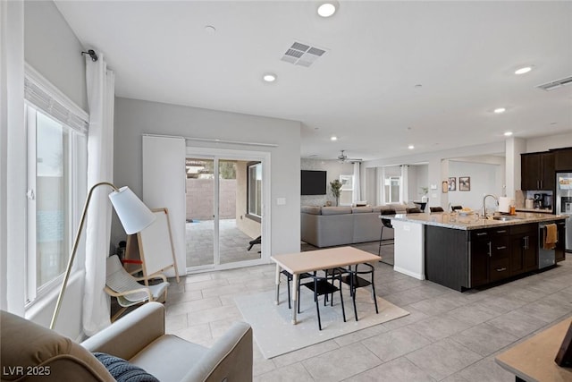 5234 Savannah Rose St, Las Vegas, NV 89149 - kitchen featuring open floor plan, light stone countertops, a center island with sink, dark brown cabinets, and light tile patterned floors