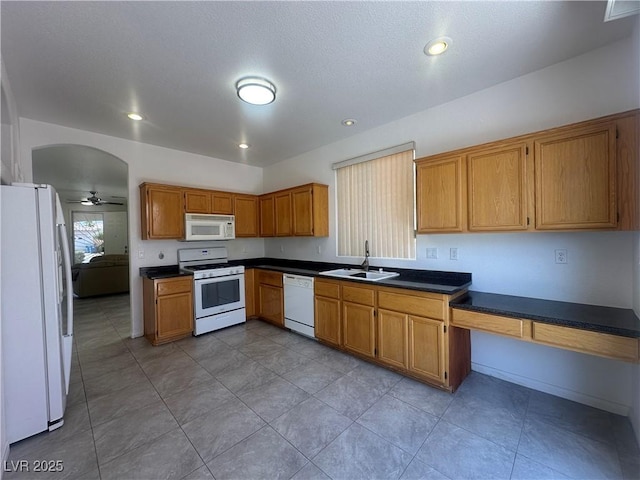 8042 Palace Monaco Ave, Las Vegas, NV 89117 - kitchen with white appliances, dark countertops, brown cabinets, ceiling fan, and light tile patterned floors