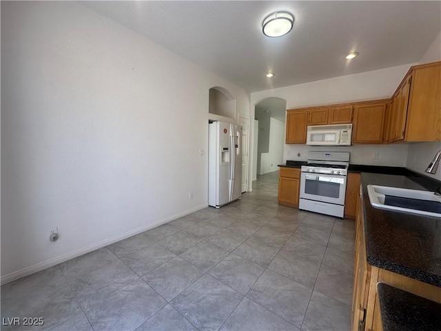 8042 Palace Monaco Ave, Las Vegas, NV 89117 - kitchen with white appliances, arched walkways, dark countertops, and light tile patterned floors