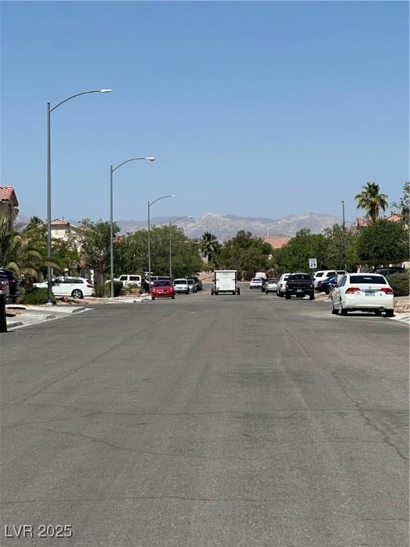 8042 Palace Monaco Ave, Las Vegas, NV 89117 - view of asphalt road with a mountain view, street lights, and curbs