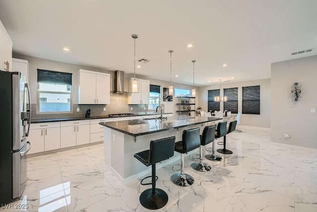 6834 Compass St, North Las Vegas, NV 89084 - kitchen with stainless steel appliances, wall chimney exhaust hood, a kitchen bar, healthy amount of natural light, and recessed lighting