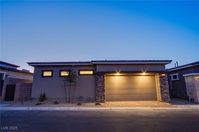 909 Allister Fields Ln, Las Vegas, NV 89138 - view of front of house featuring stucco siding, a garage, decorative driveway, and stone siding