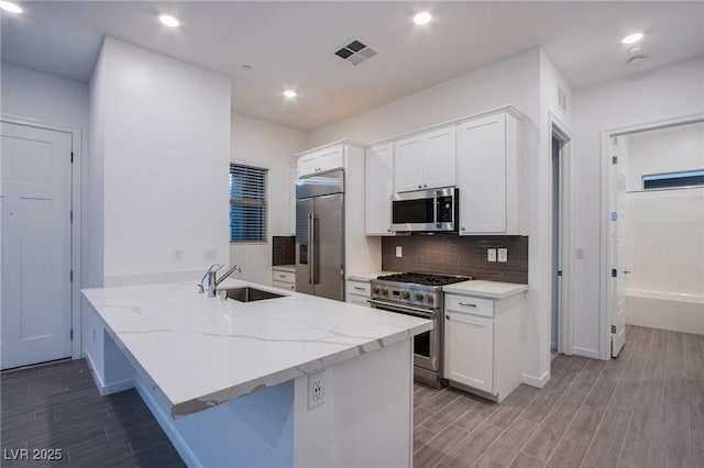 909 Allister Fields Ln, Las Vegas, NV 89138 - kitchen featuring high quality appliances, wood finished floors, white cabinetry, decorative backsplash, and light stone countertops