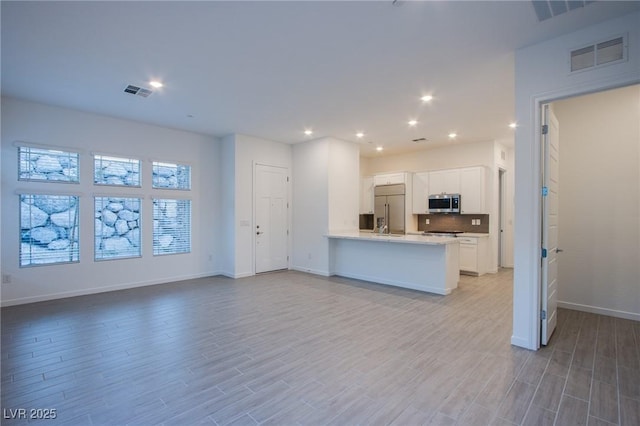 909 Allister Fields Ln, Las Vegas, NV 89138 - kitchen with appliances with stainless steel finishes, white cabinets, light countertops, open floor plan, and light wood-style flooring